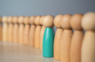 One painted wooden pawn stands slightly out of line from a row of perfectly aligned identical plain pawns, suggesting OCD in the attention-grabbing departure from a pattern, and the distinctiveness of Ketamine as a Treatment for OCD